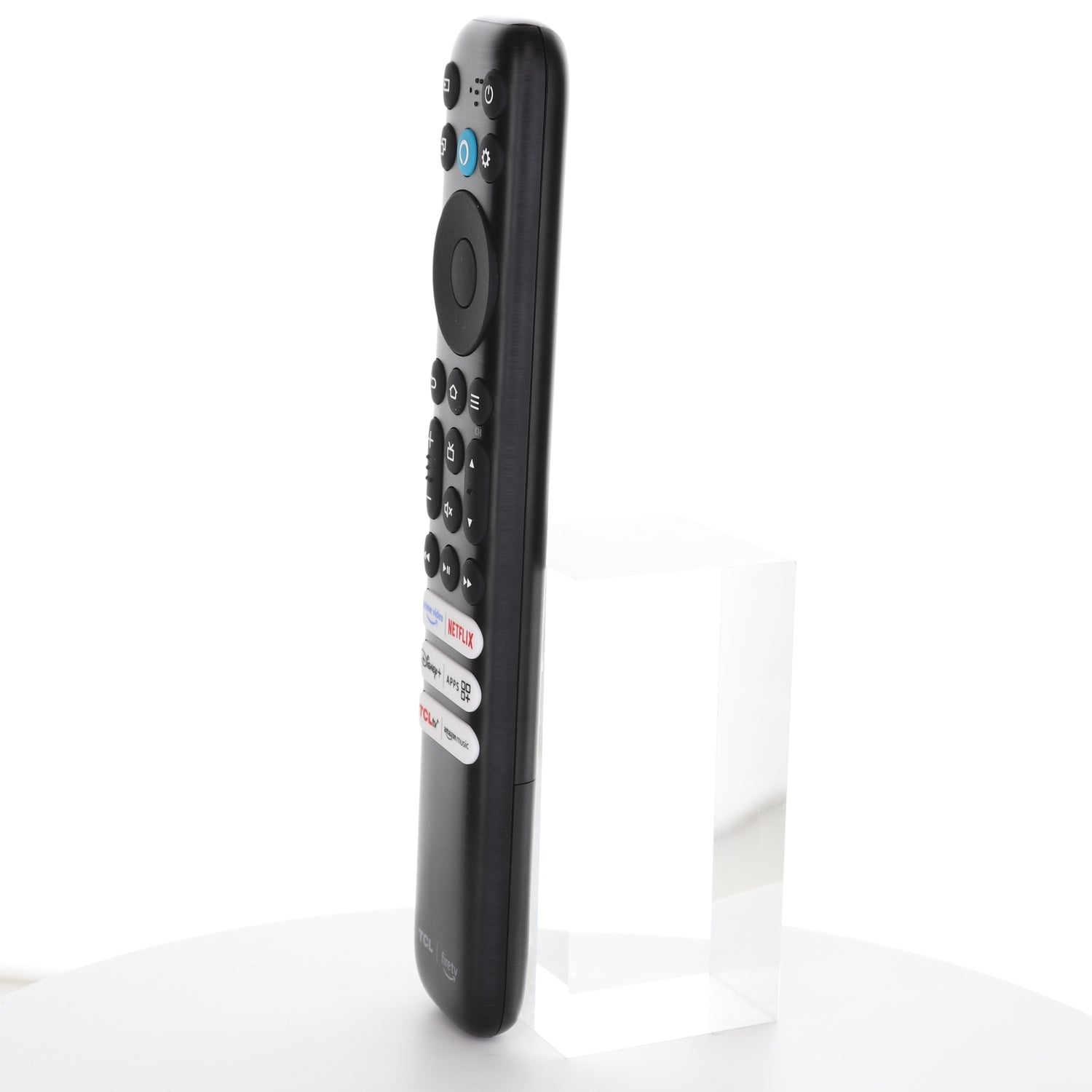 A TCL RC813 CMB1 Amazon Alexa Fire TV Remote Control (Q550F) stands upright on a clear block against a white background, showcasing shortcut keys for Netflix, Prime Video, TCLtv+, Disney+, and Amazon Music.