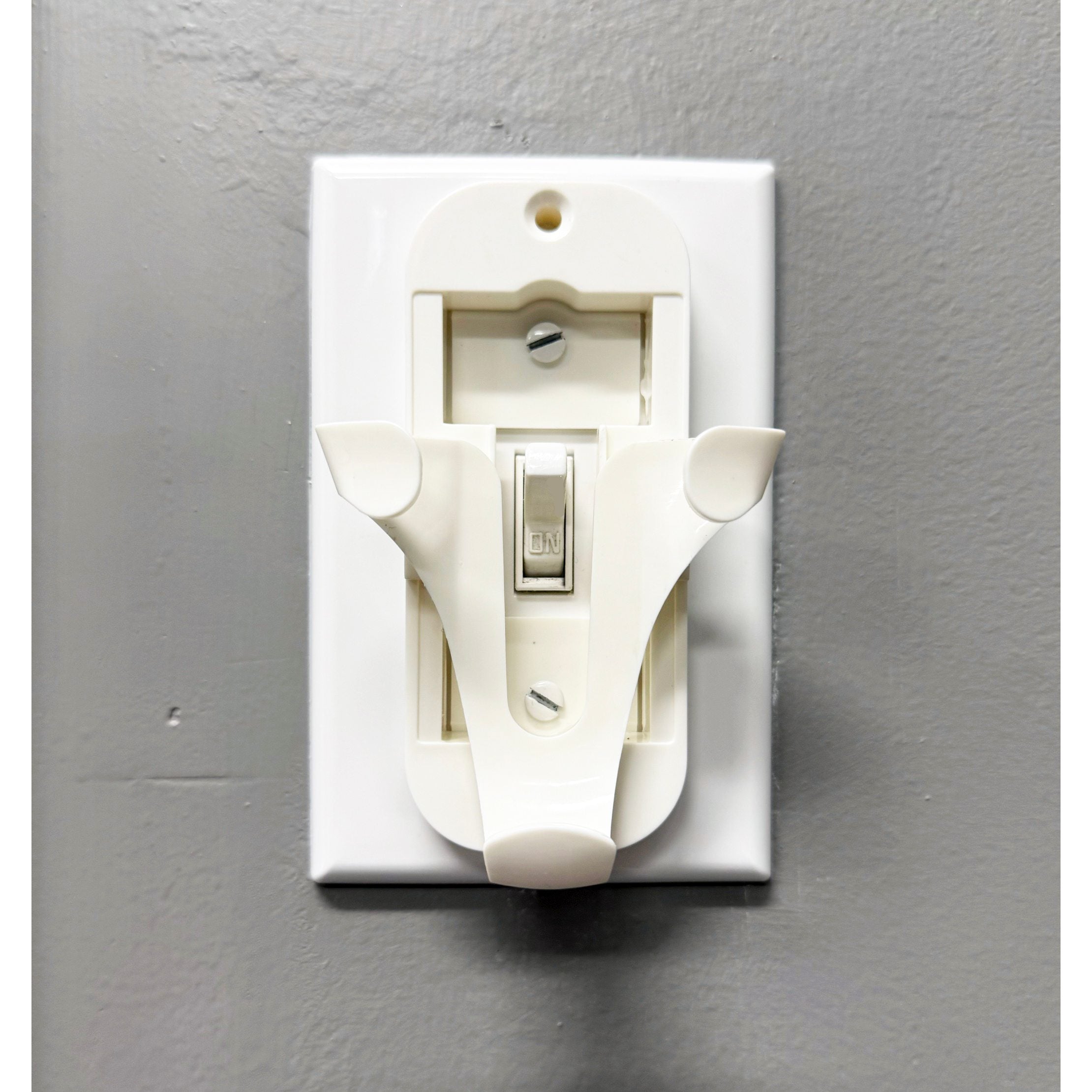The white Anderic 99122 / 99123 wall mount bracket for Hunter Ceiling Fan remotes easily installs on gray surfaces, offering a sleek cover for the standard switch beneath.