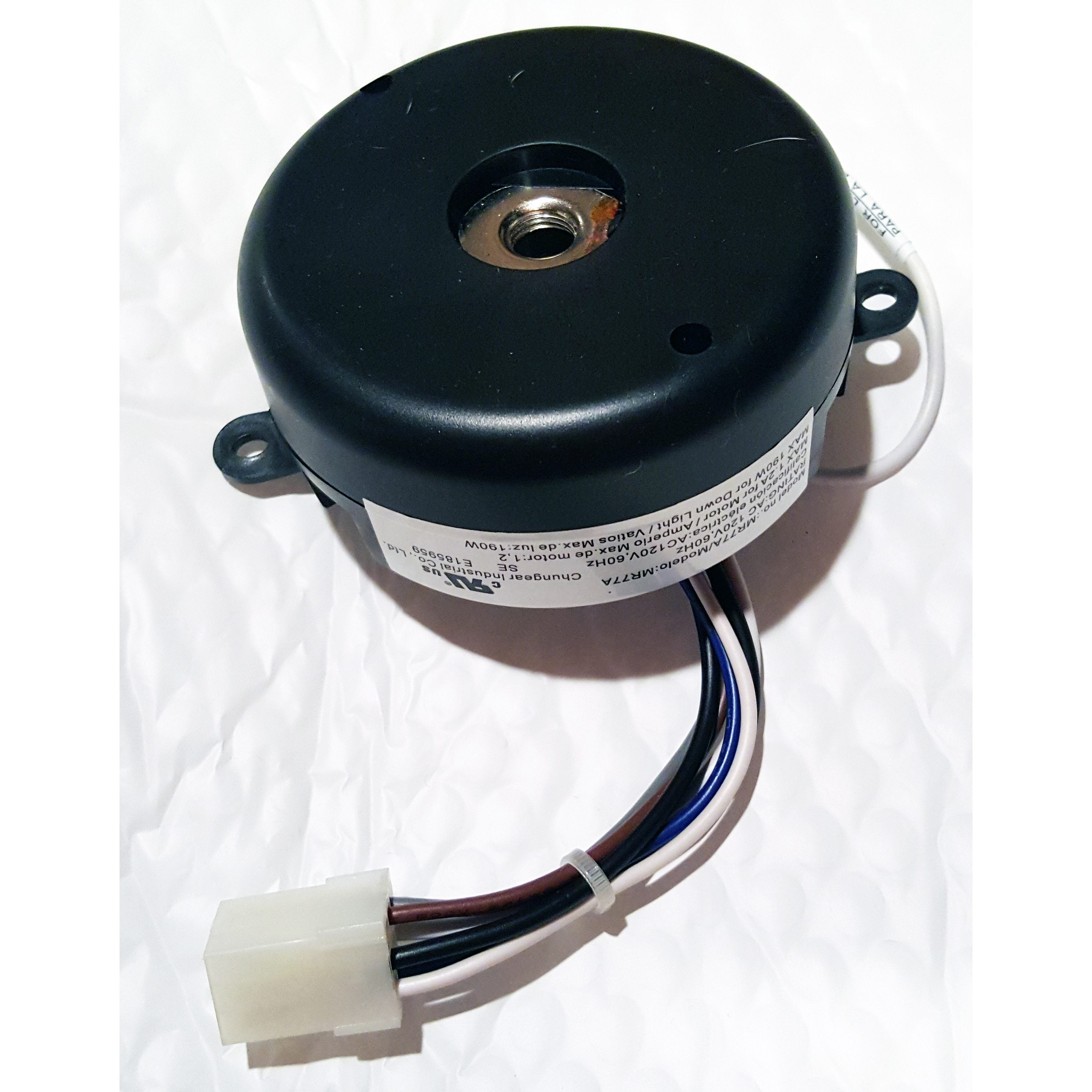 A Home Decorators Collection MR77A Ceiling Fan Remote Control Kit, featuring a round black motor with a central hole, mounting tabs, attached wires, and a white connector, is shown on a textured white surface.