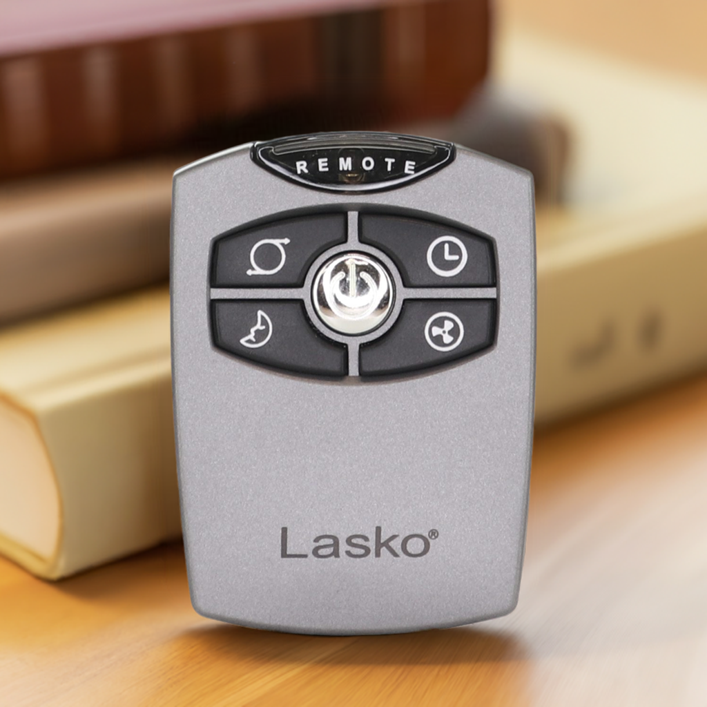 A Lasko 2033651 Upright Fan Remote Control with five buttons stands upright on a table before stacked books, ready to operate your Elite Wind Tower or Space Saving Pedestal fan.