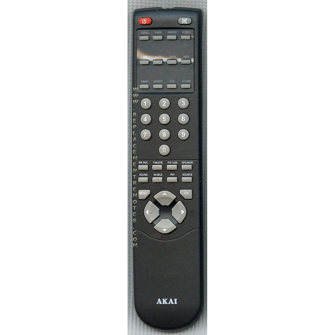 The black Akai 790002517A1 TV remote control, featuring buttons like power, volume, numbers, and navigation arrows, sits on a gray surface.