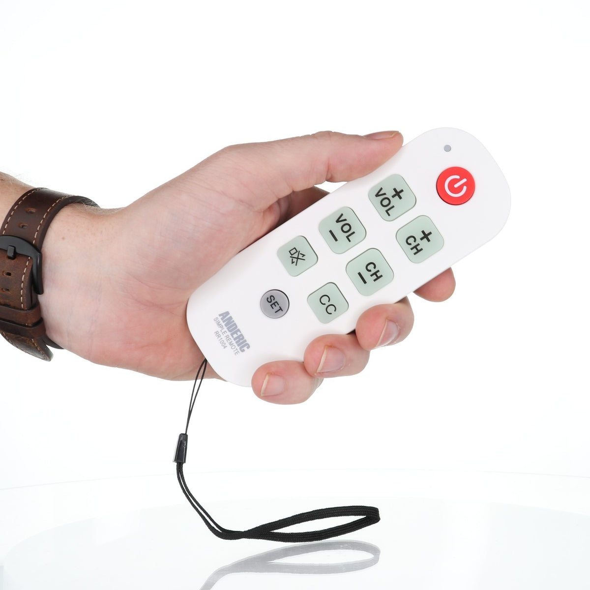 Anderic RR1004 universal TV remote with large glow-in-the-dark buttons and a wrist strap held in a hand